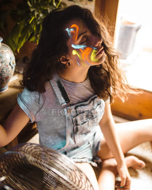 Молода жінка з різною флуоресцентною фарбою на обличчі . — стокове фото