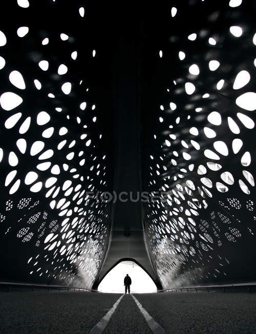 Silhouette standing on road in tunnel with carved holes. — Stock Photo