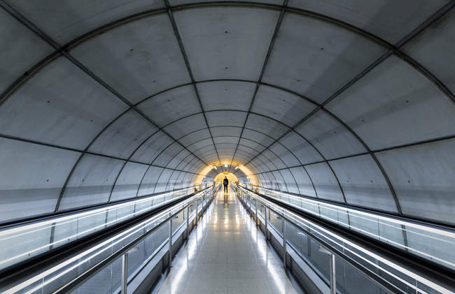 Unrecognizable person standing in empty tube with moving walkways. — Stock Photo