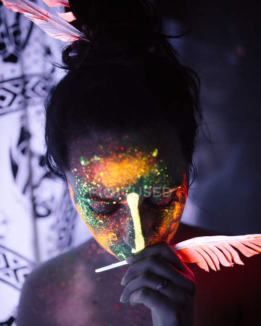 Портрет женщины со светящейся краской и пером — стоковое фото