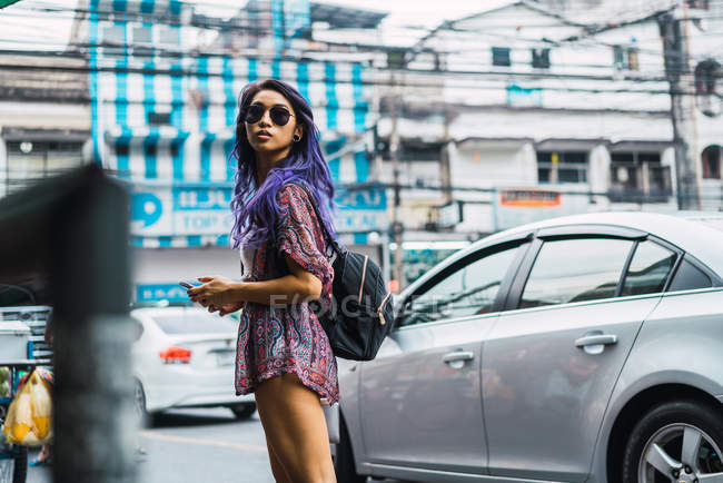 Hübsche Frau mit lila Haaren, Sonnenbrille und Blick zurück auf die Straße — Stockfoto