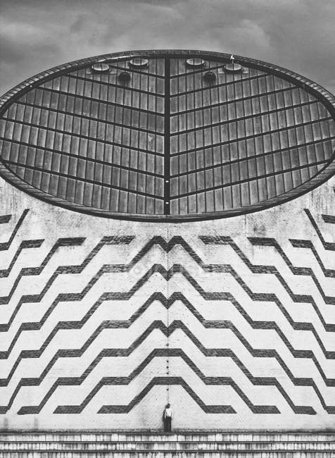 Далекий взгляд на человека, стоящего у большого бетонного необычного здания . — стоковое фото