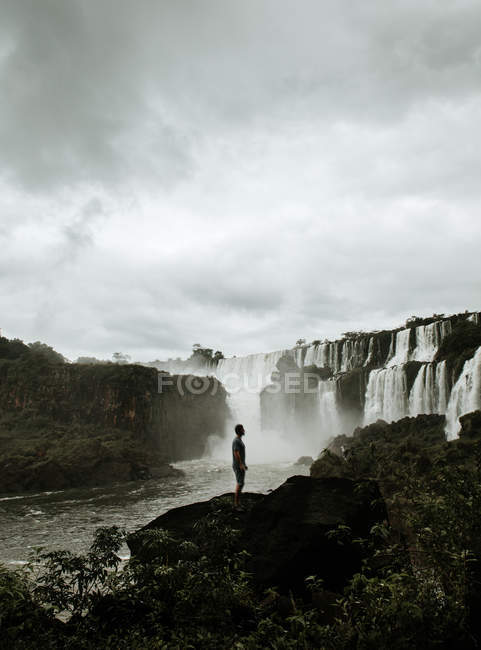 Tourist standing over waterfall cascade on background — Stock Photo