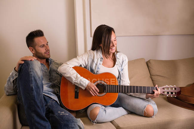 Жінка грає на гітарі для хлопця вдома — стокове фото
