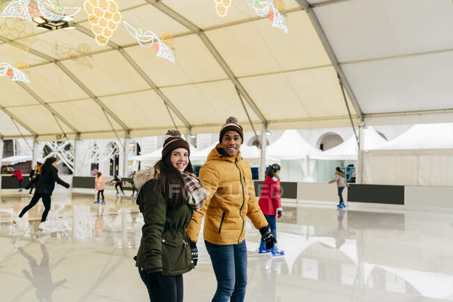 Cheerful couple holding hands on rink — Stock Photo