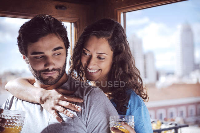 Romántica pareja joven tomando jugo y abrazándose en casa - foto de stock