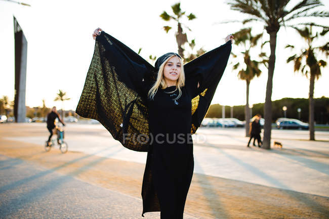 Stylische Frau posiert mit warmer Jacke auf sonnenbeschienener Straße — Stockfoto