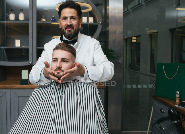Barber styling beard of male customer — Stock Photo