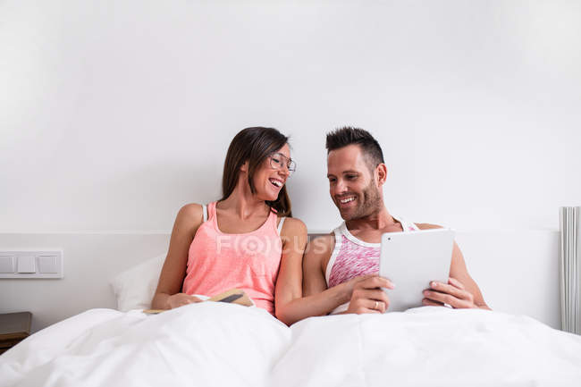 Fröhliches Paar mit Tablette im Bett — Stockfoto