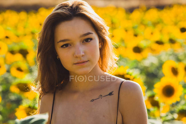Hübsche junge Frau posiert in Sonnenblumen — Stockfoto