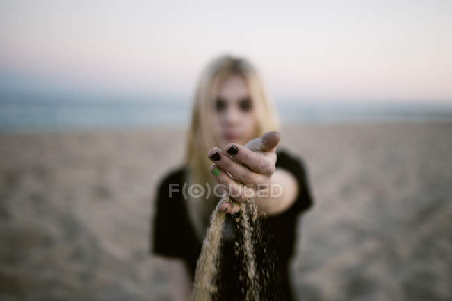 Mujer mano vertiendo arena a la orilla del mar - foto de stock