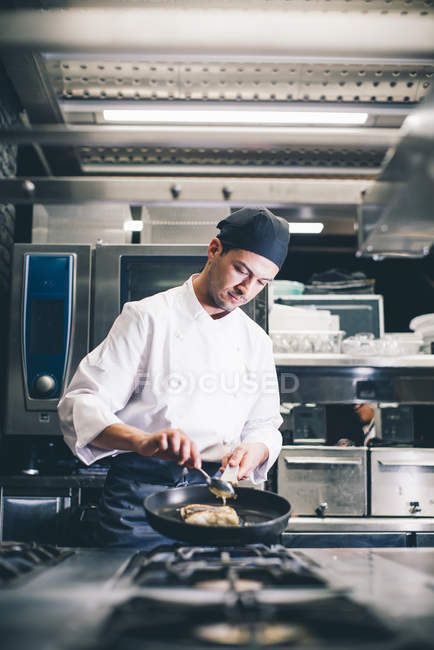 Cook frying meat on pan at restaurant kitchen — Stock Photo