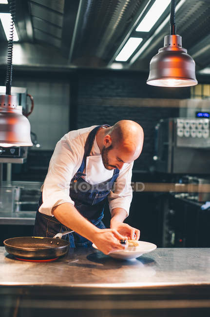 Koch steht auf Küche des Restaurants und serviert Teller mit Essen. — Stockfoto