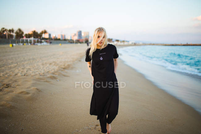 Jovem loira caminhando na praia arenosa — Fotografia de Stock