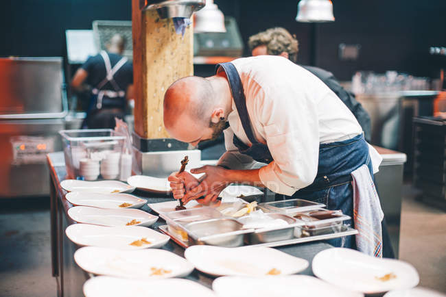Koch serviert Gerichte in Restaurantküche — Stockfoto