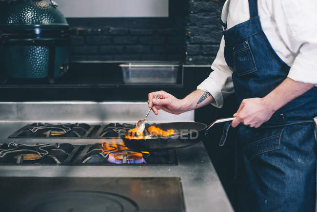 Crop cook cooking flambe on stove — Stock Photo