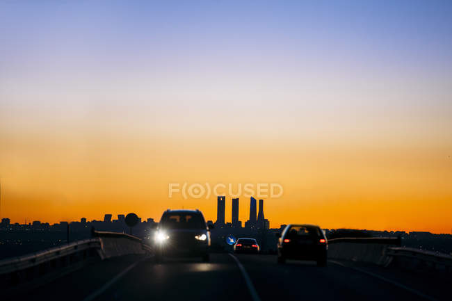 Дорога с силуэтами автомобилей, движущихся в движении по вечернему небу — стоковое фото