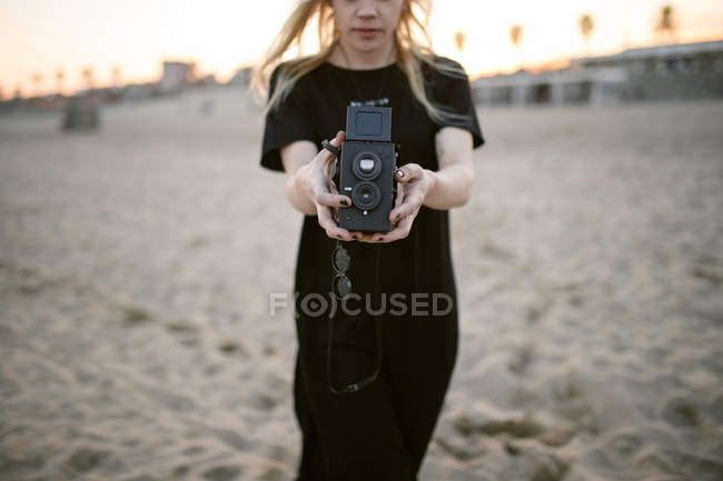 Blonde Frau auf Sand mit Kamera — Stockfoto