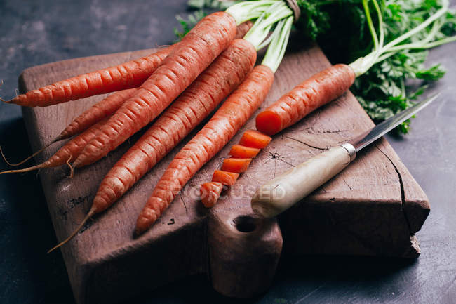 Fresh sliced carrots in wooden cutting board — Stock Photo