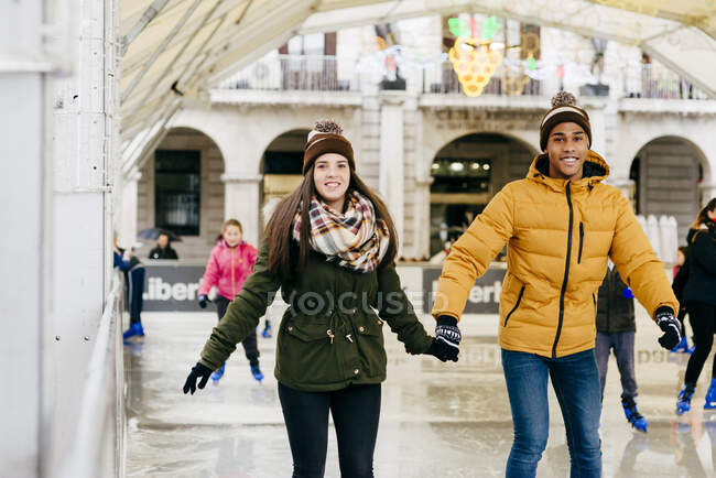 Весела пара тримає руки на ковзанах — стокове фото