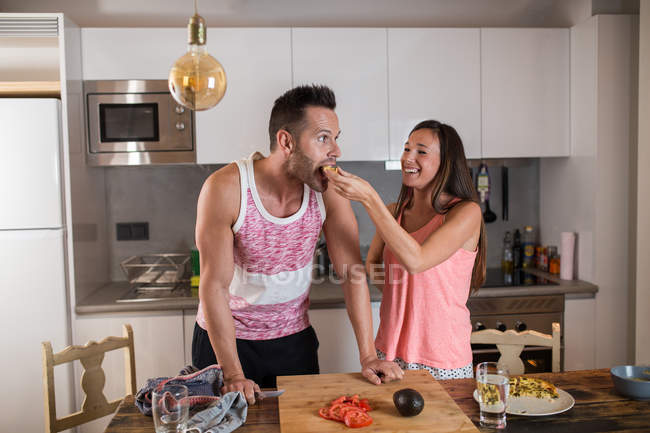 Menina jovem alimentando namorado em casa — Fotografia de Stock