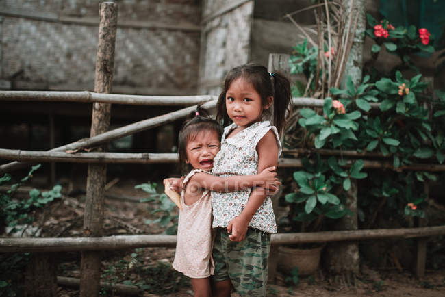 Laos, 4000 Inseln: Entzückendes Mädchen weint und umarmt Schwester auf Dorfstraße. — Stockfoto