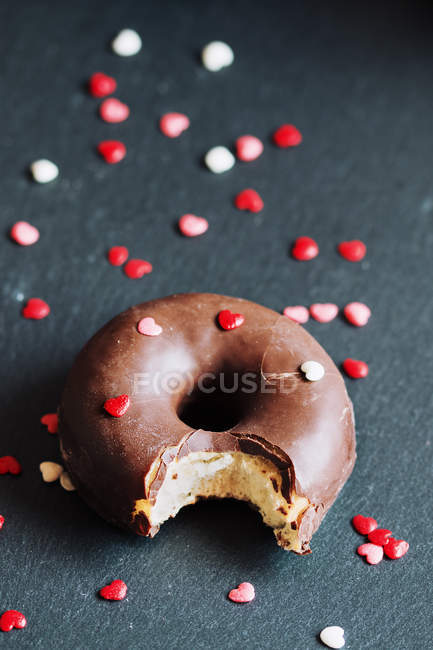 Donut de chocolate mordido con coberturas - foto de stock