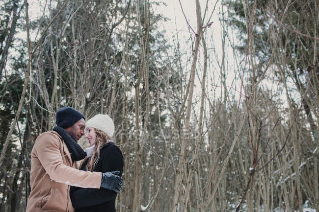 Multiracial casal de ligação na floresta de inverno — Fotografia de Stock
