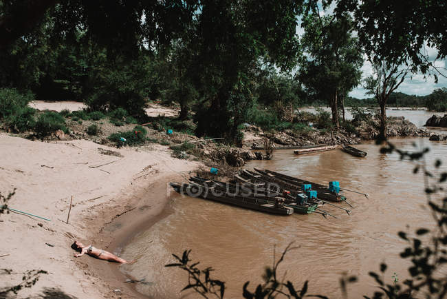 Човни причаїлися на березі брудної річки — стокове фото