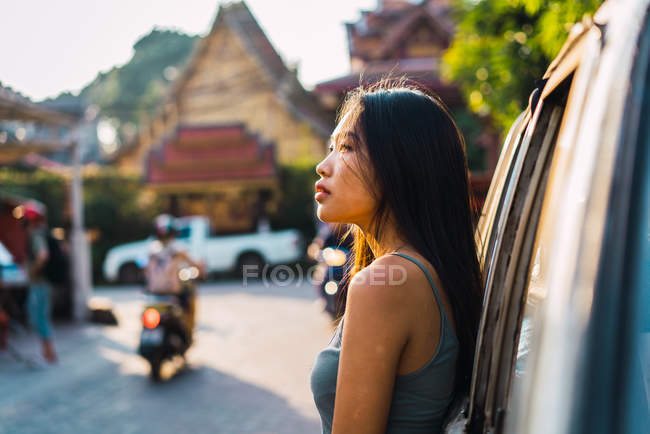 Jeune femme penchée sur la voiture sur la scène de rue — Photo de stock