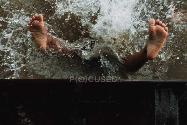 Legs of anonymous child falling from boat in  water after — Stock Photo