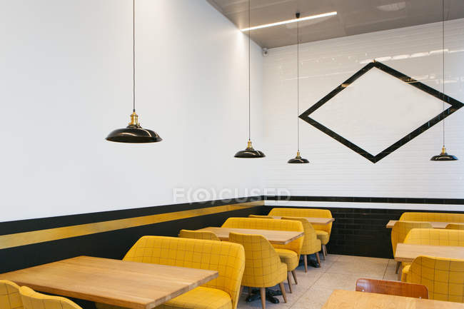 Empty tables and yellow chairs in cafe — Stock Photo