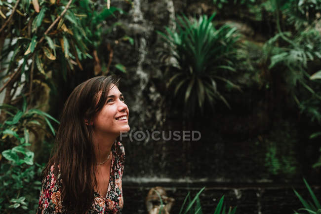 Seitenansicht des lächelnden brünetten Mädchens auf Hintergrund Palmen — Stockfoto