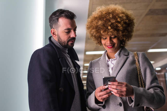Elegante coppia in cappotti di navigazione smartphone — Foto stock
