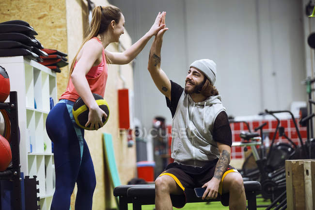 Fröhlich sportlicher Mann und Frau gibt High Five beim Training im Fitnessstudio. — Stockfoto