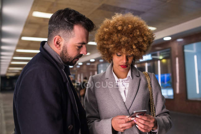 Couple élégant naviguant smartphone au passage — Photo de stock