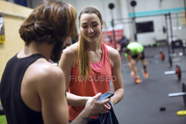 Cheerful fit people with smartphones in gym — Stock Photo