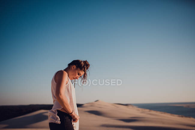 Vista lateral de mujer bonita posando sobre fondo de dunas de arena - foto de stock