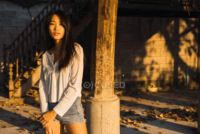 Asiatin posiert an Säule und schaut in Kamera — Stockfoto