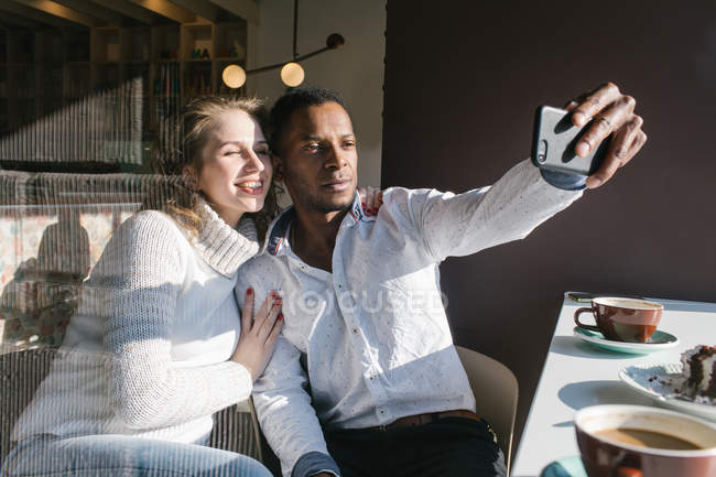 Casal tirando selfie com smartphone no café — Fotografia de Stock