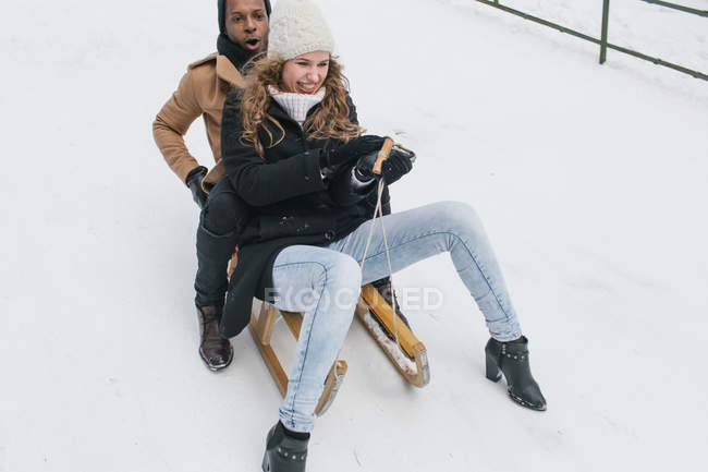 Pareja feliz montar en trineo en la colina nevada y divertirse . - foto de stock