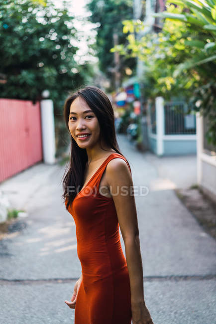 Femme joyeuse en robe rouge posant sur la rue — Photo de stock