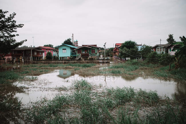 Vista para a grande poça e pequenas casas rurais coloridas em dia nublado
. — Fotografia de Stock