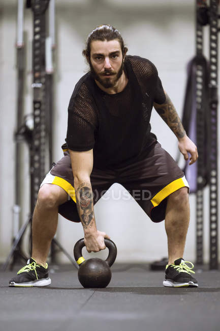 Sportlicher Mann steht im Fitnessstudio und trainiert mit Hantel. — Stockfoto