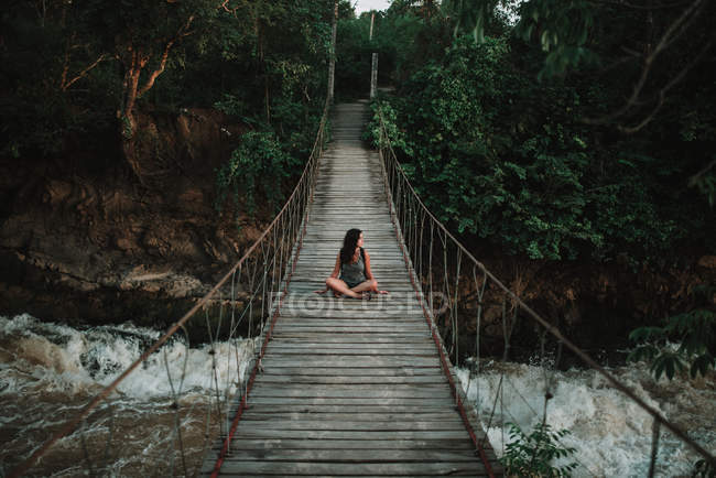 Morena mulher sentada na ponte de corda em trópicos — Fotografia de Stock