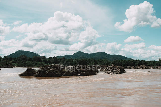 Вид на брудну тропічну річку під яскравим хмарним пейзажем — стокове фото