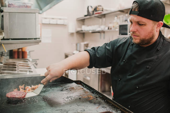 Чоловік стоїть і перетворює пиріжки під час приготування їжі на кухні ресторану . — стокове фото