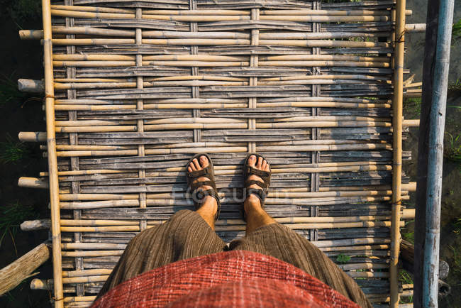 Looking down view of legs standing on straw path. — Stock Photo