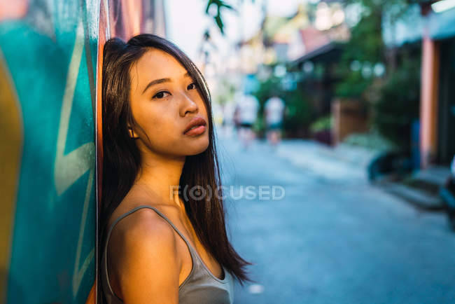 Nachdenkliche Frau lehnt an blauer Tür und blickt in Kamera — Stockfoto
