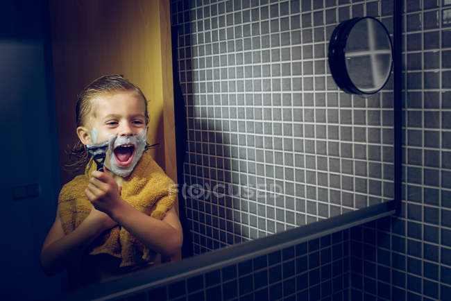 Niño afeitándose en el espejo del baño - foto de stock